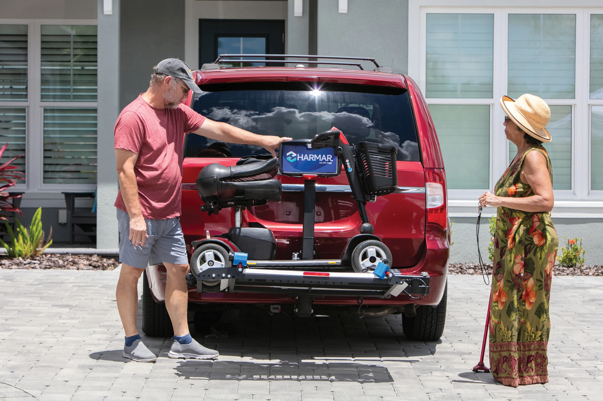 Harmar vehicle platform lift carrying a mobility scooter behind a red SUV